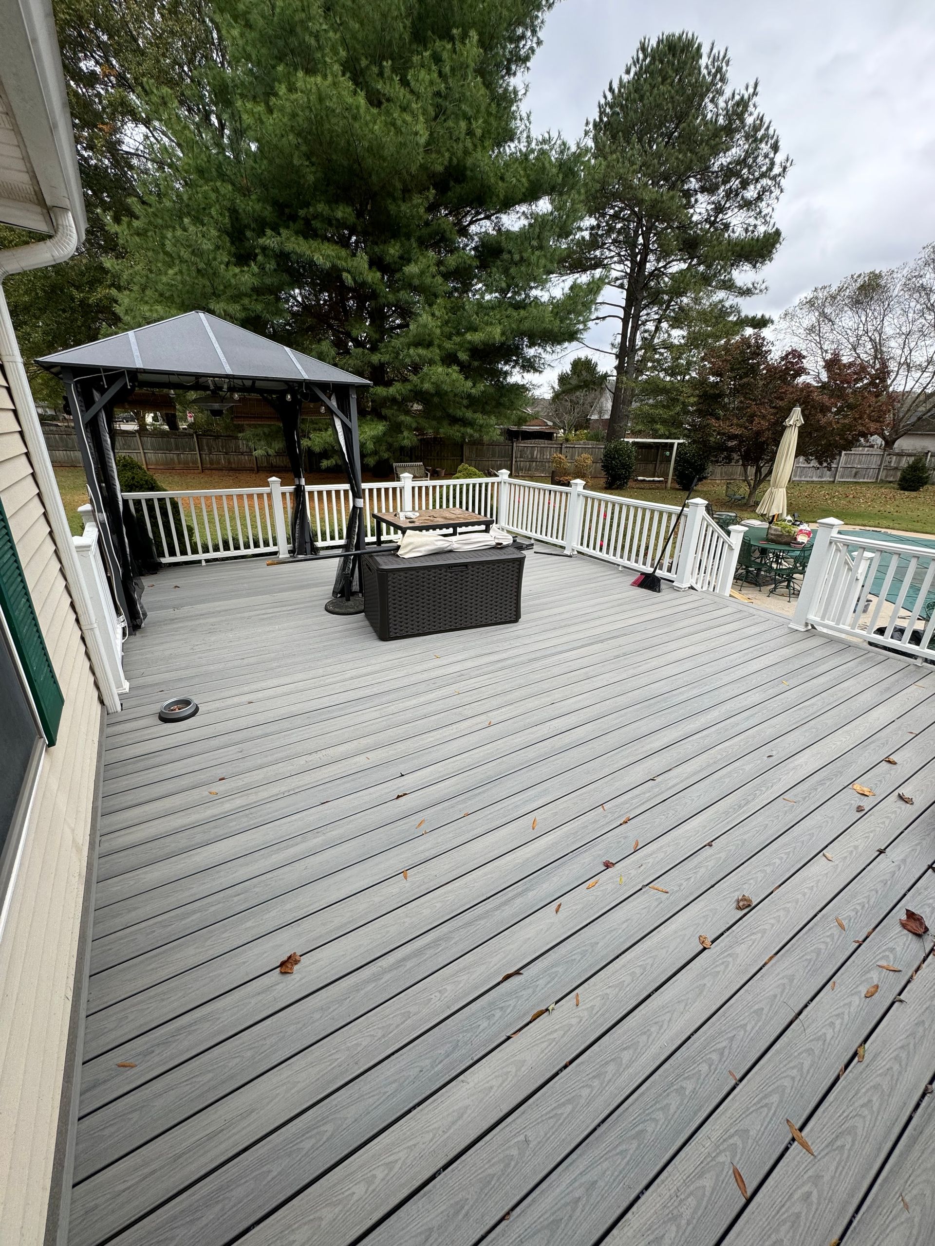 Large gray composite backyard deck with white railings and a covered gazebo built by Warner's Remodeling