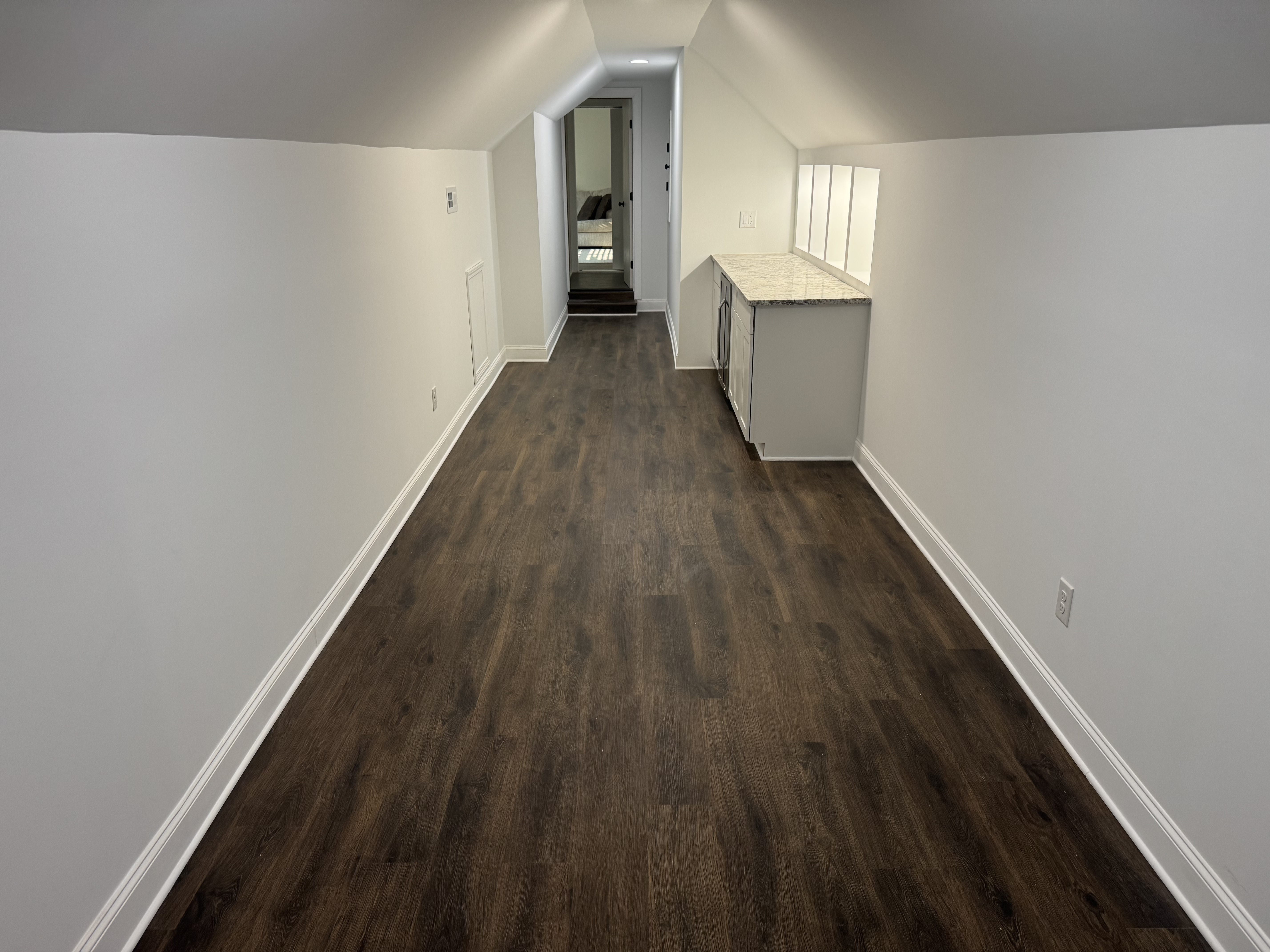 Newly installed dark luxury vinyl plank flooring in a finished bonus room