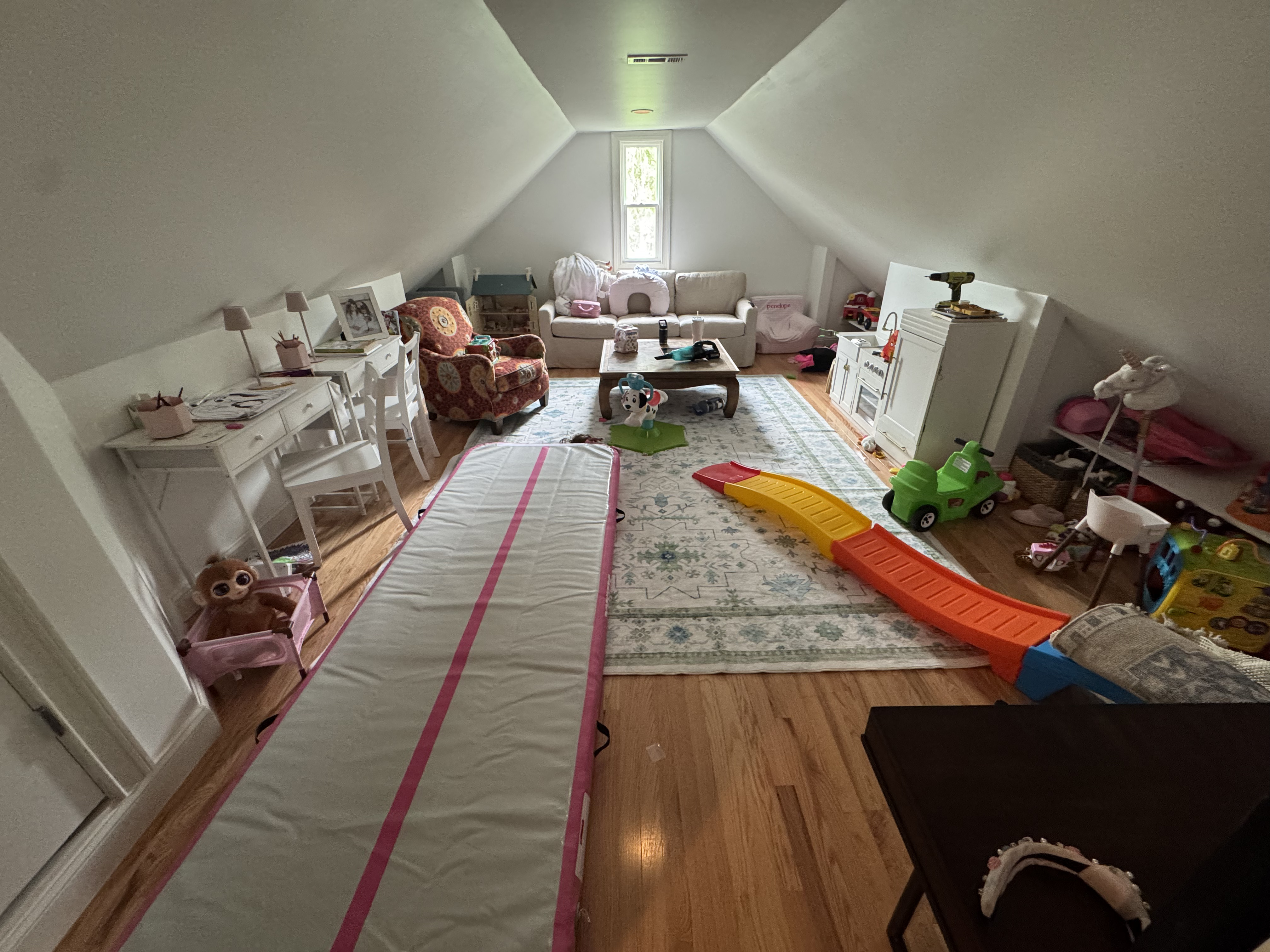 Finished attic bonus room addition with sloped ceilings and hardwood floors used as a playroom