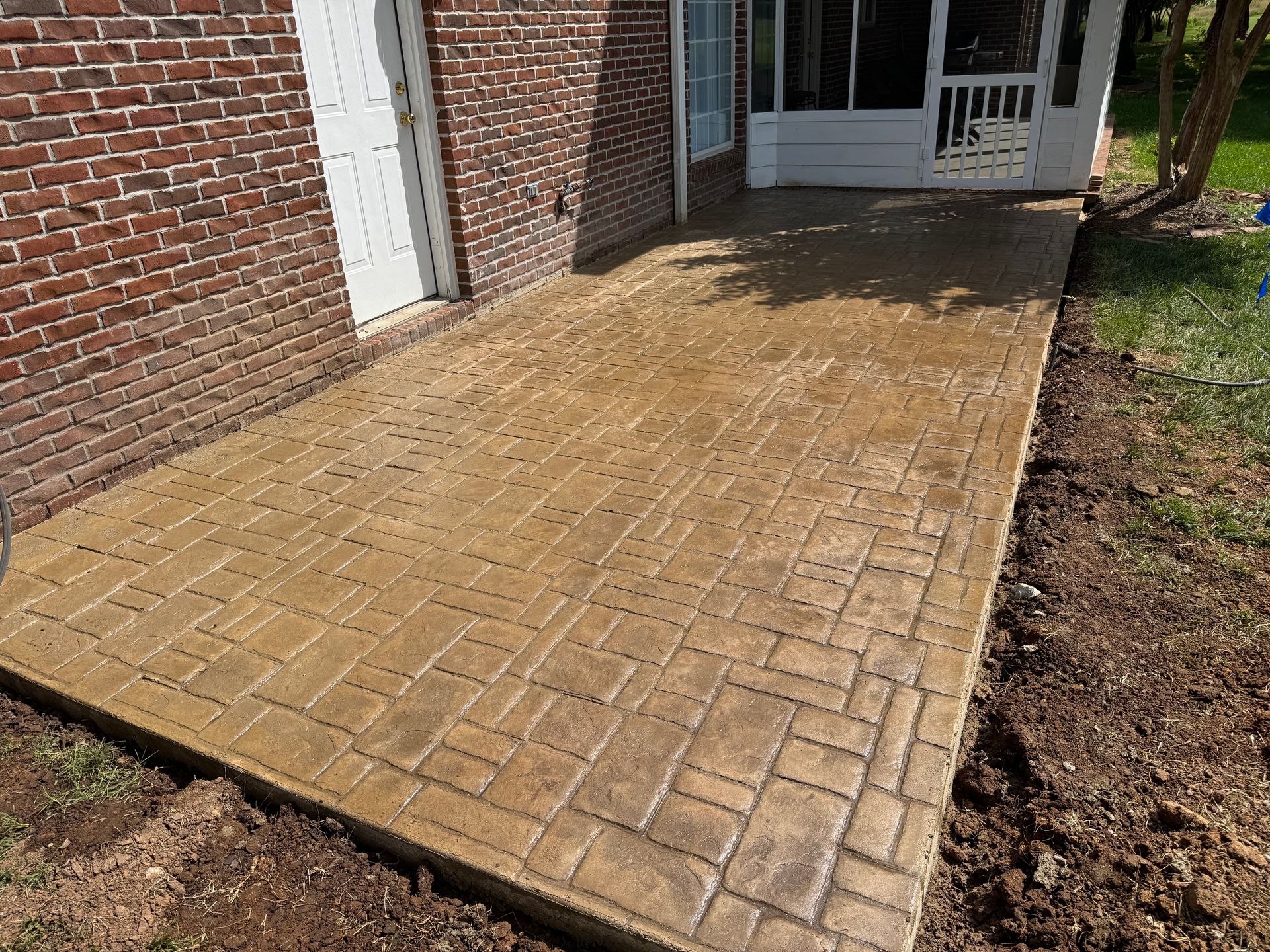 Brick-pattern stamped concrete patio installed behind a brick home